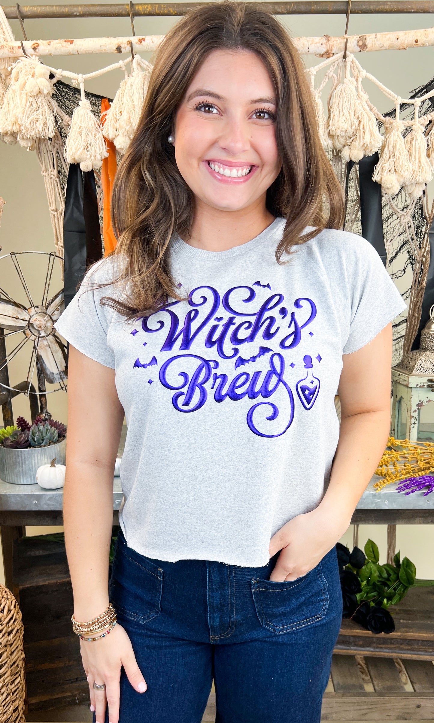 Cute model wearing the Witch's Brew Halloween Edgy Graphic Shirt, showcasing its fun Halloween design. Perfect for festive vibes!