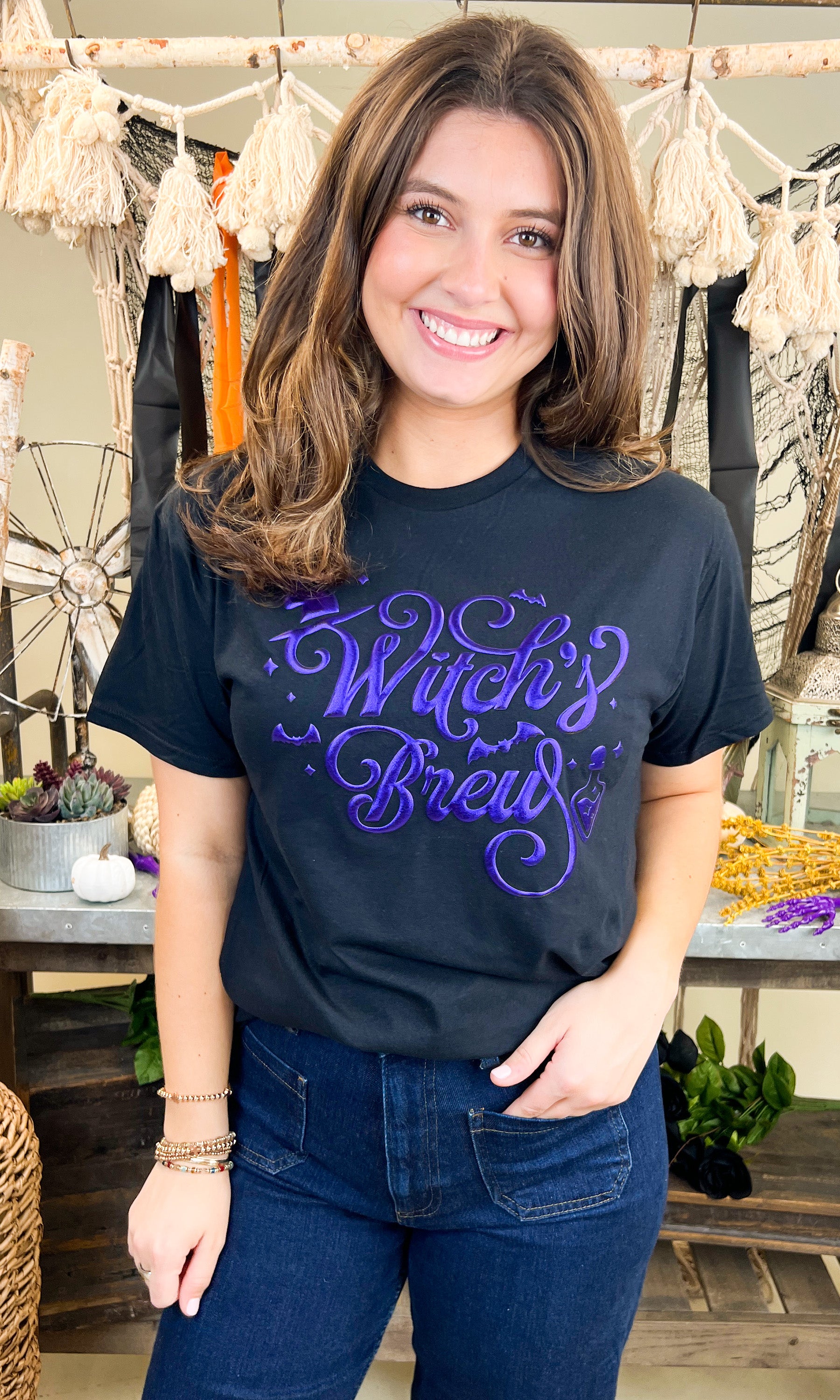 Stylish model wearing a Witch's Brew Halloween Graphic Shirt, perfect for festive celebrations and seasonal fun.